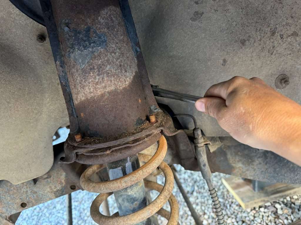 Turning the four 13mm nuts that hold the shock tower at the top of the spring seat is easy. If there is too much rust, those studs will break.