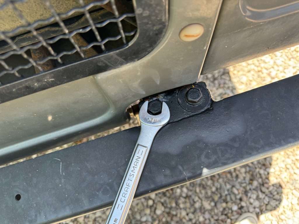 Two 17mm bolts at the end of each frame rail. I used an open end wrench to stay away from the painted grille.