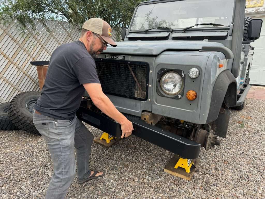 Sliding the winch bumper onto the frame of the 1991 Land Rover Defender 110 HCPU