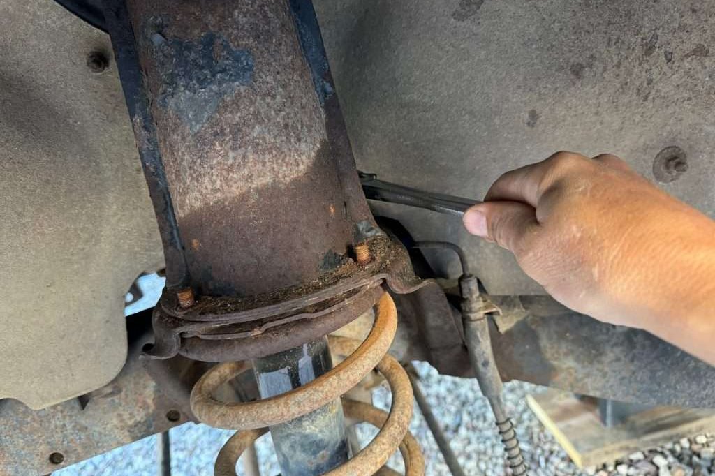 Turning the four 13mm nuts that hold the shock tower at the top of the spring seat is easy. If there is too much rust, those studs will break.