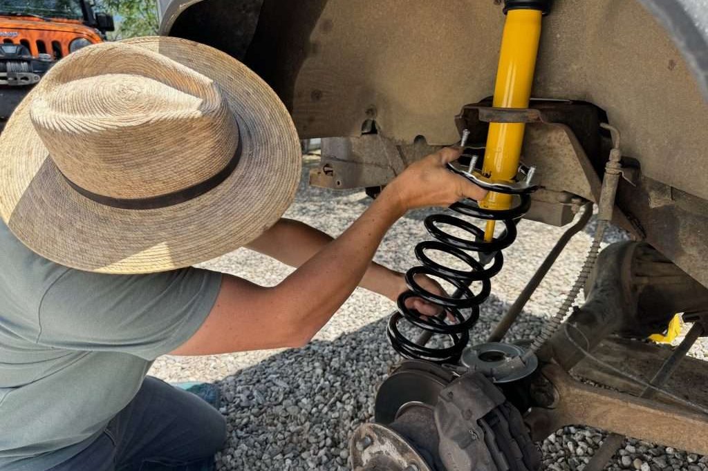 Sliding the new coil spring into position for a new front suspension on the Land Rover Defender 110