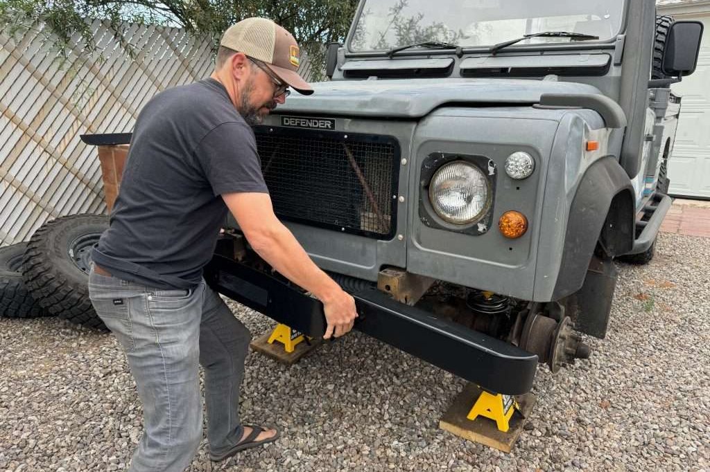 Sliding the winch bumper onto the frame of the 1991 Land Rover Defender 110 HCPU