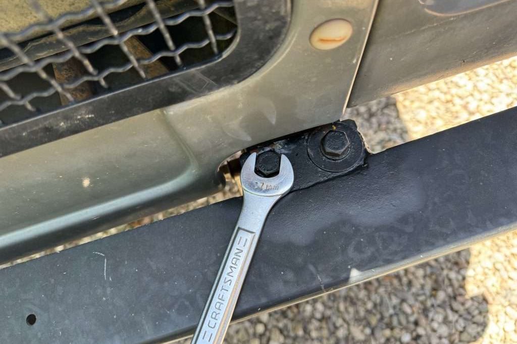 Two 17mm bolts at the end of each frame rail. I used an open end wrench to stay away from the painted grille.